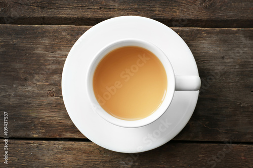 Cup of tea with milk on wooden background, top view