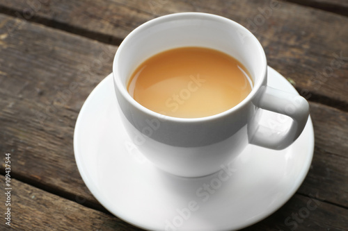 Cup of tea with milk on wooden background