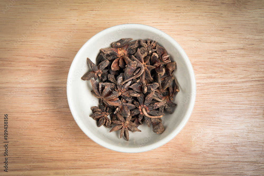 bowl of anise seed on a wood background bowl of anise seed on a wood background