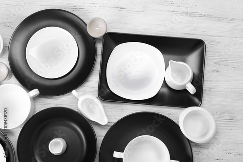 Black and white empty dishes on white wooden background.