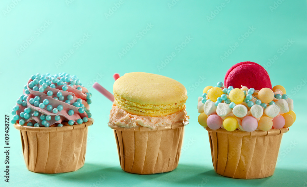 Tasty cupcakes with macaroon on turquoise background Tasty cupcakes with macaroon on turquoise background