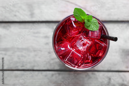 Glass of cherry soda with ice and fresh mint on rustic wooden background