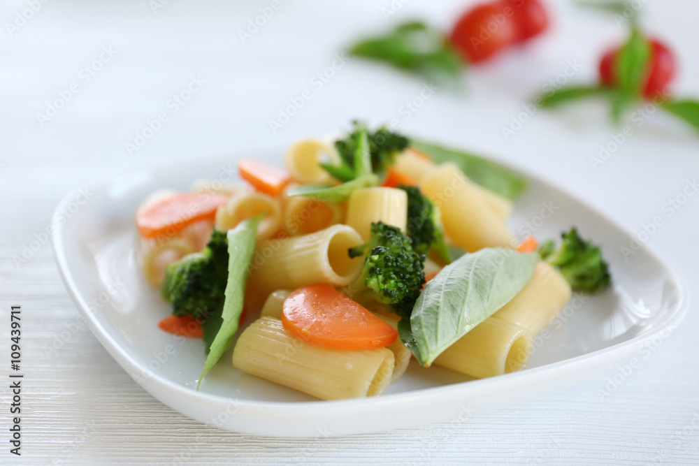 Boiled rigatoni pasta with carrot, broccoli and basil on white plate Boiled rigatoni pasta with carrot, broccoli and basil on white plate