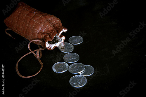 Grunge pouch with silver coins on dark background