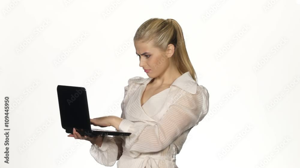 Young angry businesswoman works on notebook. White Young angry businesswoman works on notebook. White