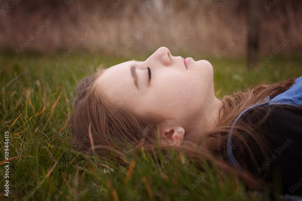Pretty teenage girl lying down on grass with her eyes closed Pretty teenage girl lying down on grass with her eyes closed