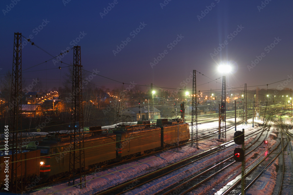 Freight train with carriages move on railways at winter night