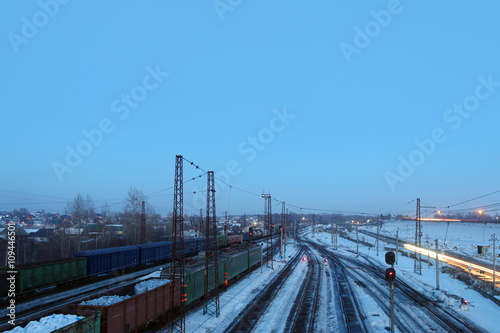 Freight trains with carriages stand on railways at snowy winter