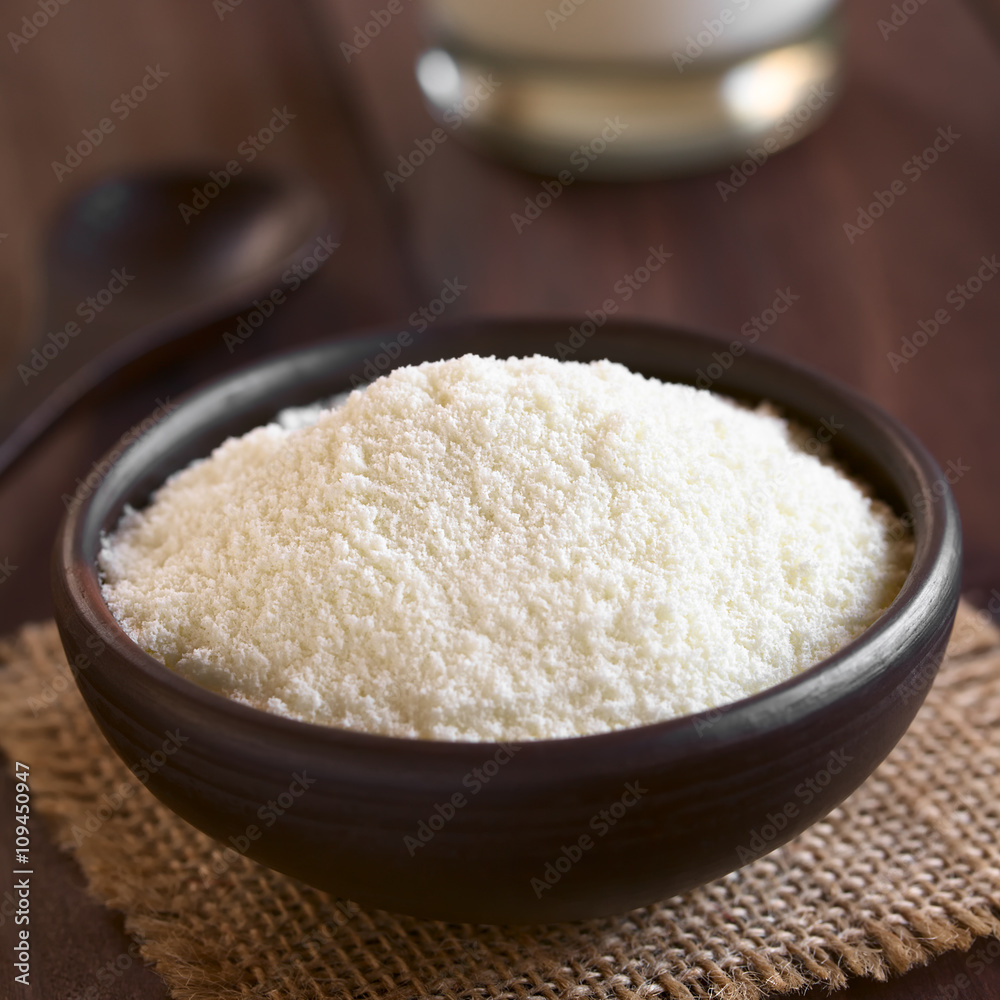 Powdered or dried milk in small bowl, photographed on dark wood with natural light (Selective Focus, Focus in the middle of the image)