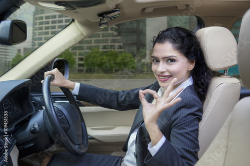Indian woman driving a car and shows OK sign © Creativa Images
