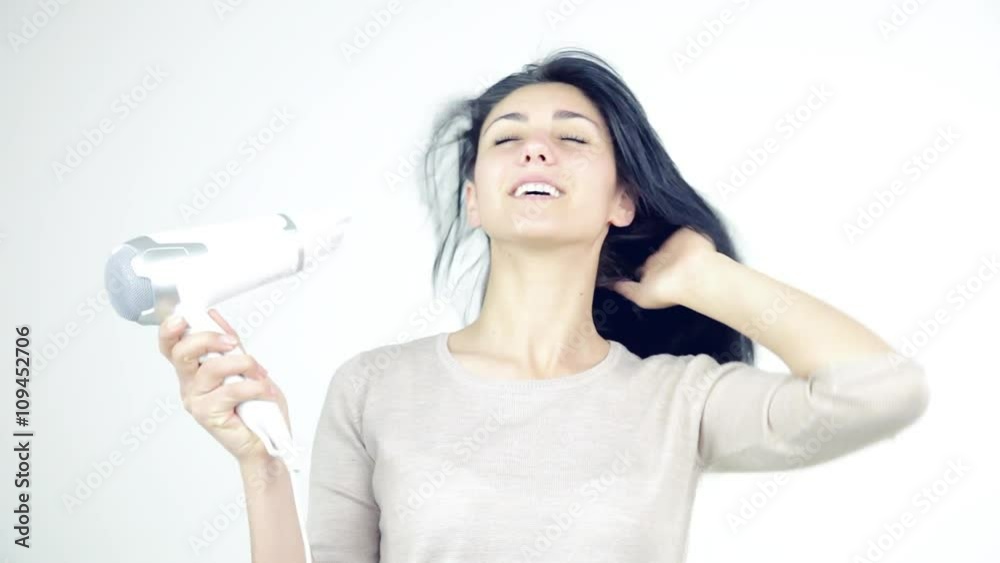 Woman having fun smiling blow drying hair isolated Woman having fun smiling blow drying hair isolated