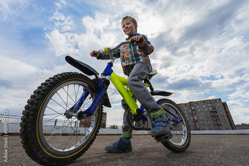 Urban biking - small happy boy and bike in city. Focus on boy