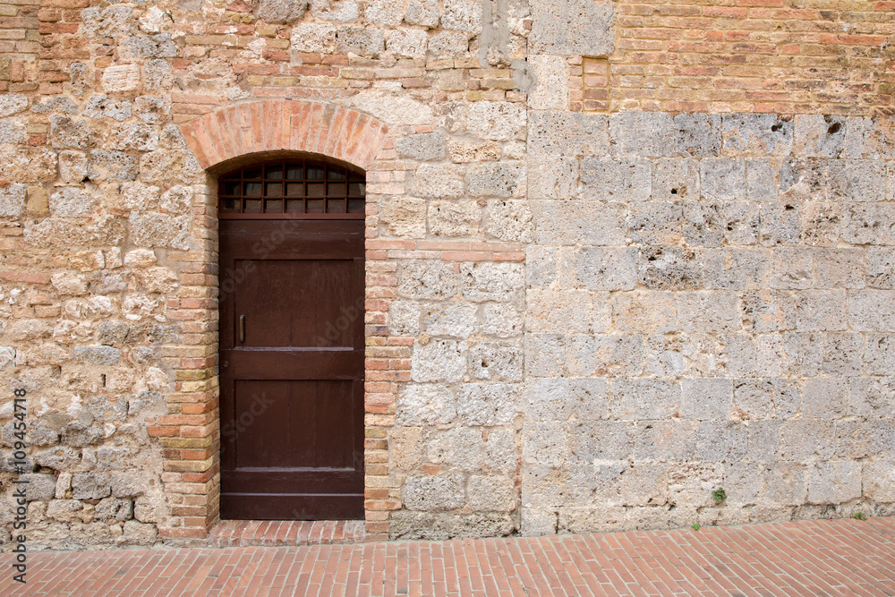 Naklejka premium Brown Door in a Medieval Tuscan Wall with Copy Space