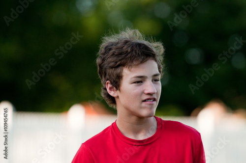 Handsome teenage boy outdoors with braces and messy hair.