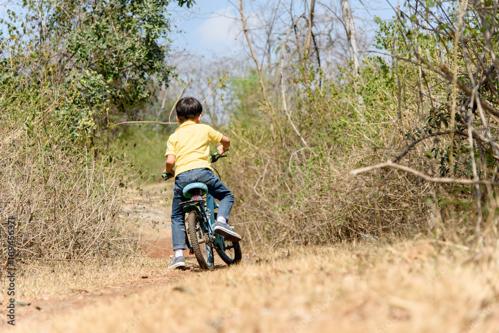 Fototapeta premium Little boy ride bicycle on the rock road.