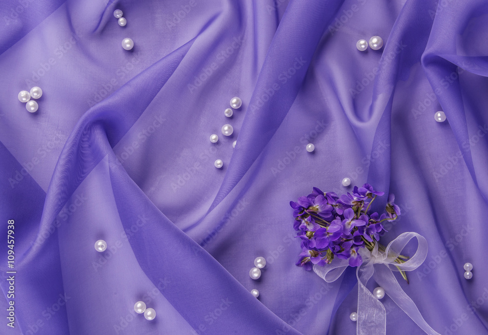pearls and bouquet of violets on the blue fabric