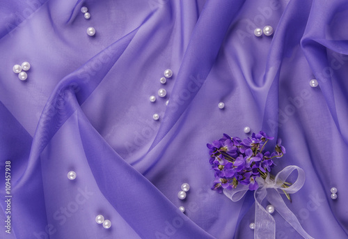pearls and bouquet of violets on the blue fabric