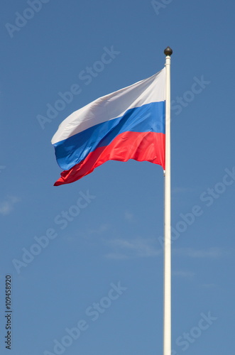 The state flag of the Russian Federation waving on blue sky background