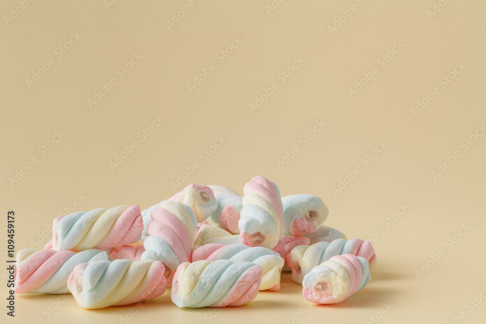 Colored twisted marshmallow on beige background Colored twisted marshmallow on beige background