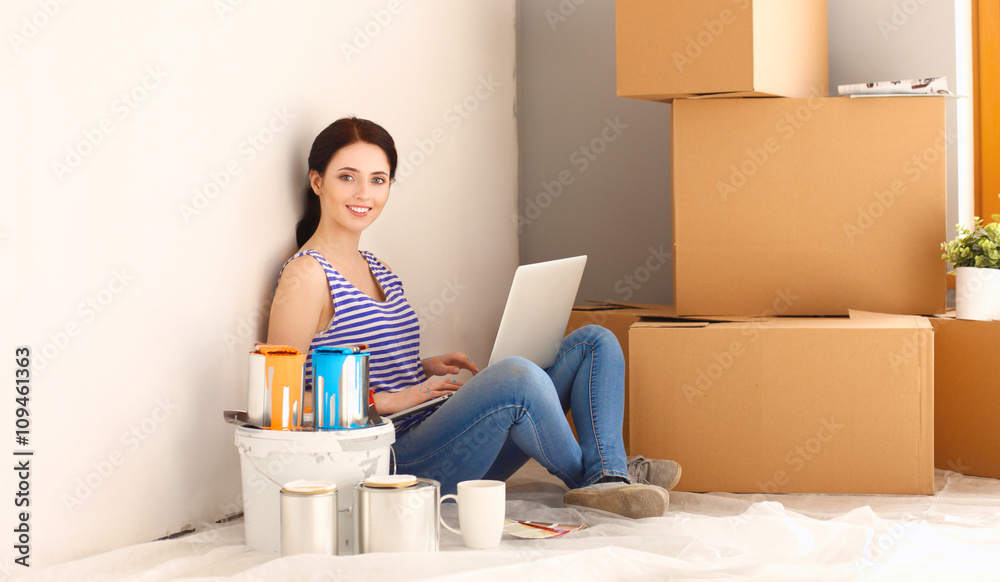 Young woman portrait while painting new apartment ,sitting with laptop Young woman portrait while painting new apartment ,sitting with laptop