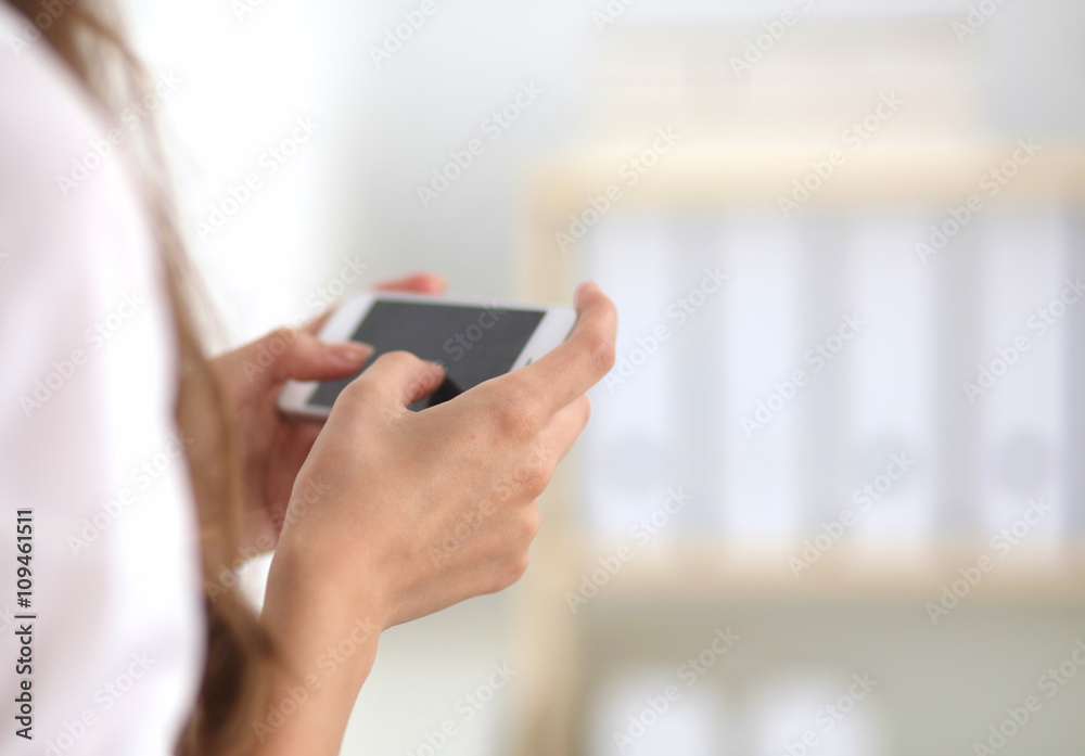 Businesswoman sending message with smartphone sitting in the office Businesswoman sending message with smartphone sitting in the office