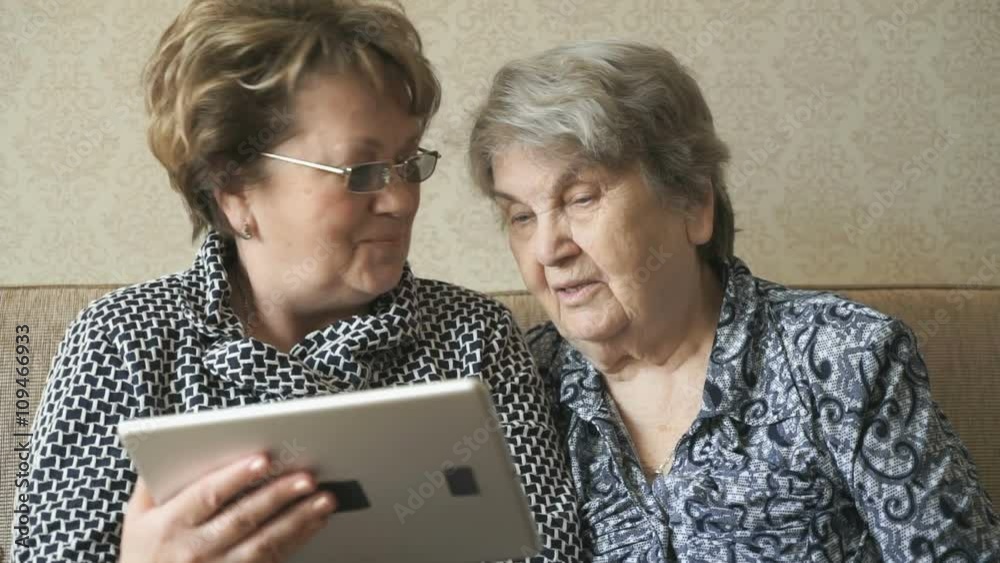 Two women watching photos on a digital tablet Two women watching photos on a digital tablet
