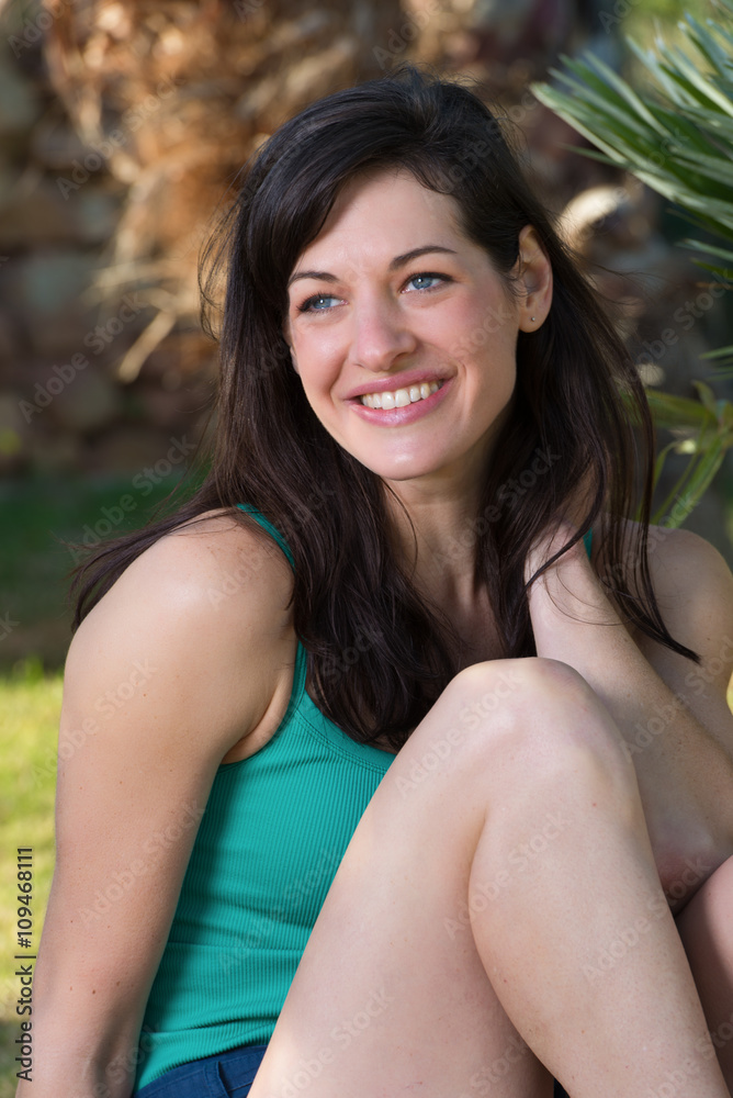 Portrait of beautiful young woman relaxing on grass with palm trees in background Portrait of beautiful young woman relaxing on grass with palm trees in background