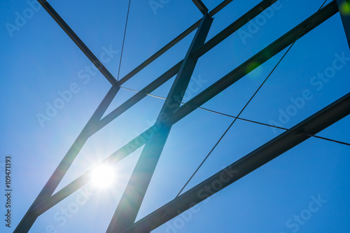 Steel construction with sky background and shining sun. Sun beams. Modern business building construction. Sun burst on blue sky with steel construction.