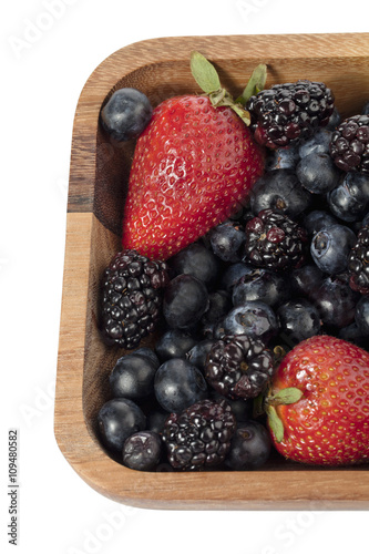 strawberries, blueberries and blackberries in wooden bowl