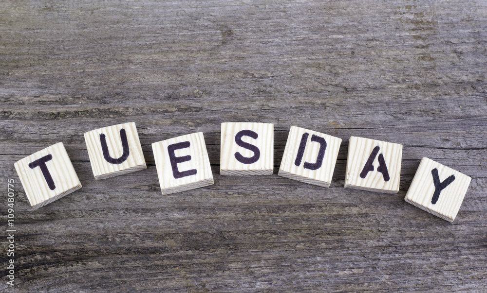 Fototapeta premium Text: Tuesday from wooden letters on wooden background