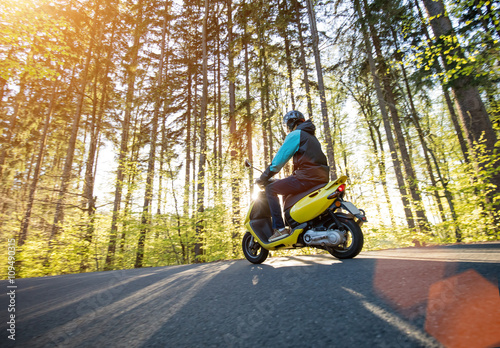 Bilde på lerret Man riding scooter on forest road.