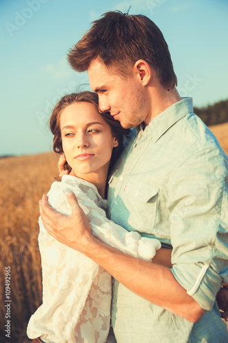 Young couple in love outdoor.Stunning sensual outdoor portrait of young stylish fashion couple posing in summer in field.Happy Smiling Couple in love.They are smiling and looking at each other © Elena Kratovich