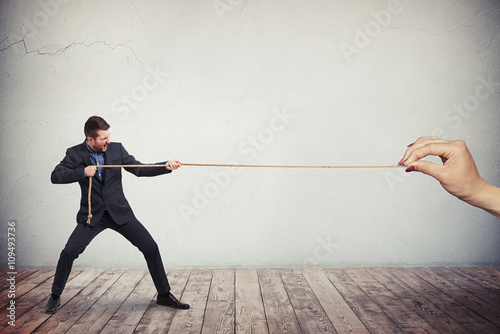 Man in business suit is pulling the rope