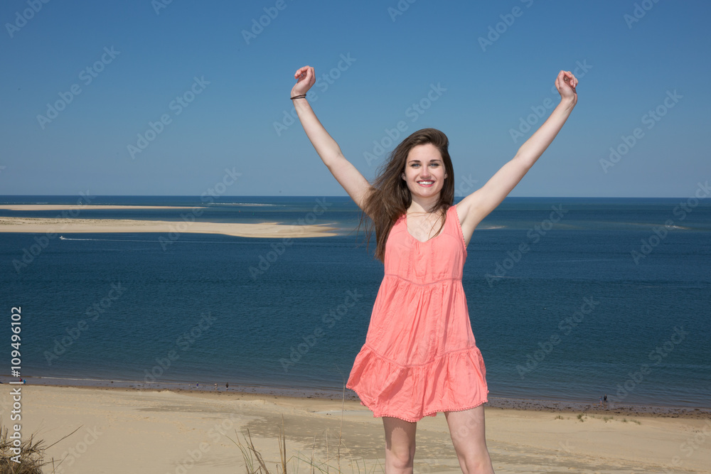Happy woman enjoying relaxing breeze and freedom by the sea. Joyful asian girl raising arms to the sky. Happy woman enjoying relaxing breeze and freedom by the sea. Joyful asian girl raising arms to the sky.