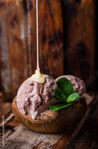 Chocolate ice cream with condenced milk on vintage wooden background. Selective focus photo