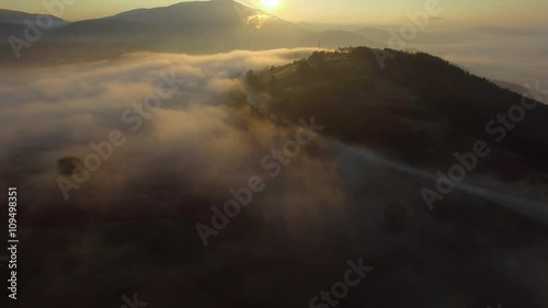 Aerial - Flying over the clouds at sunrise in the mountain 