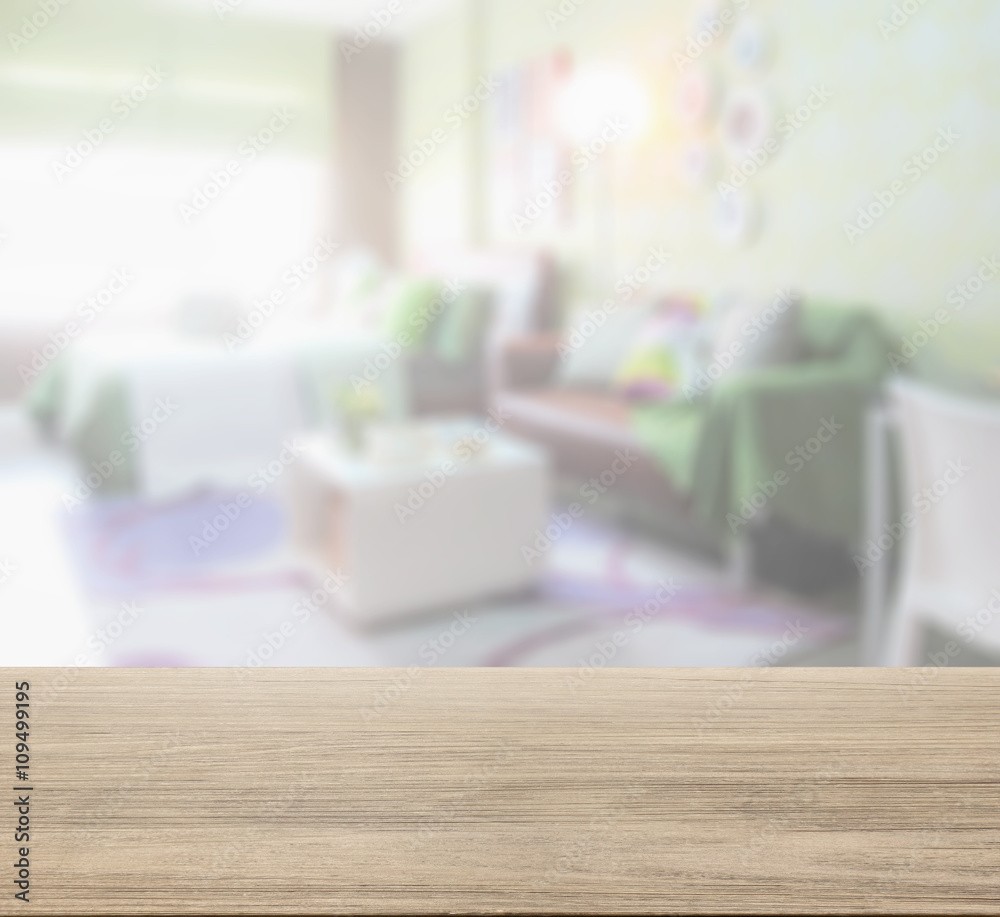 wooden table top with blur of colorful bedroom with brown sofa wooden table top with blur of colorful bedroom with brown sofa