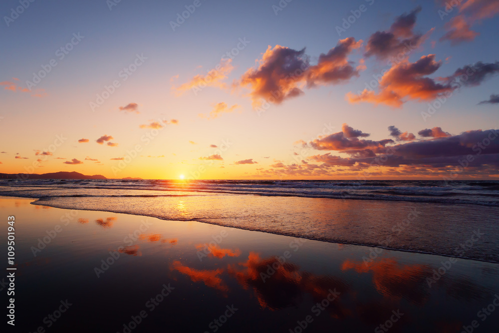 sunset on beach with cloud reflections