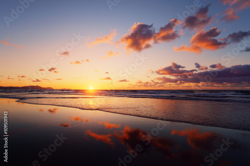 sunset on beach with cloud reflections