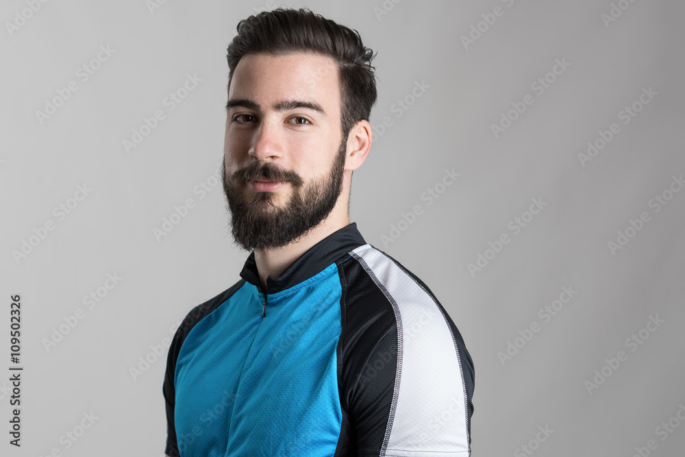 Portrait of bearded cyclist wearing jersey with copyspace looking at camera over gray studio background Portrait of bearded cyclist wearing jersey with copyspace looking at camera over gray studio background