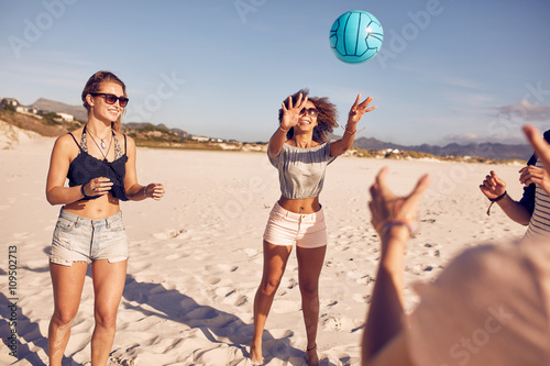 Group of friends on the beach playing volleyball