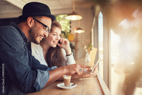 Couple using a digital tablet at coffee shop photo