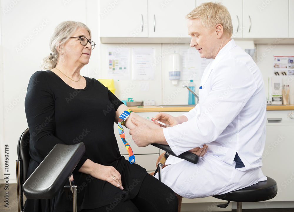 Obraz premium Doctor Collecting Senior Patient's Blood For Test In Clinic