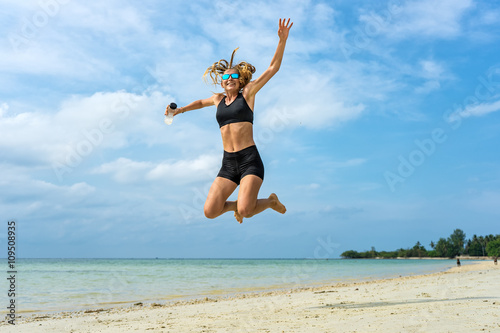 Young athletic woman jumping up on a tropical beach 