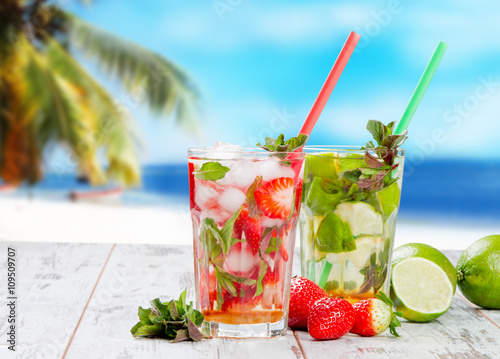 Mojito lime and strawberry drinks on wood with blur beach background