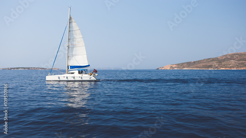 Sailing boat floating on blue sea near island