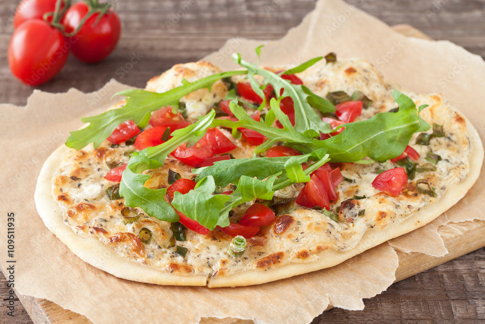Tarte flambee, an alsatian pizza, with tomatoes and arugula Tarte flambee, an alsatian pizza, with tomatoes and arugula