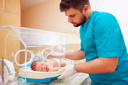 Fotografía young adult man taking care of newborn baby in infant incubator