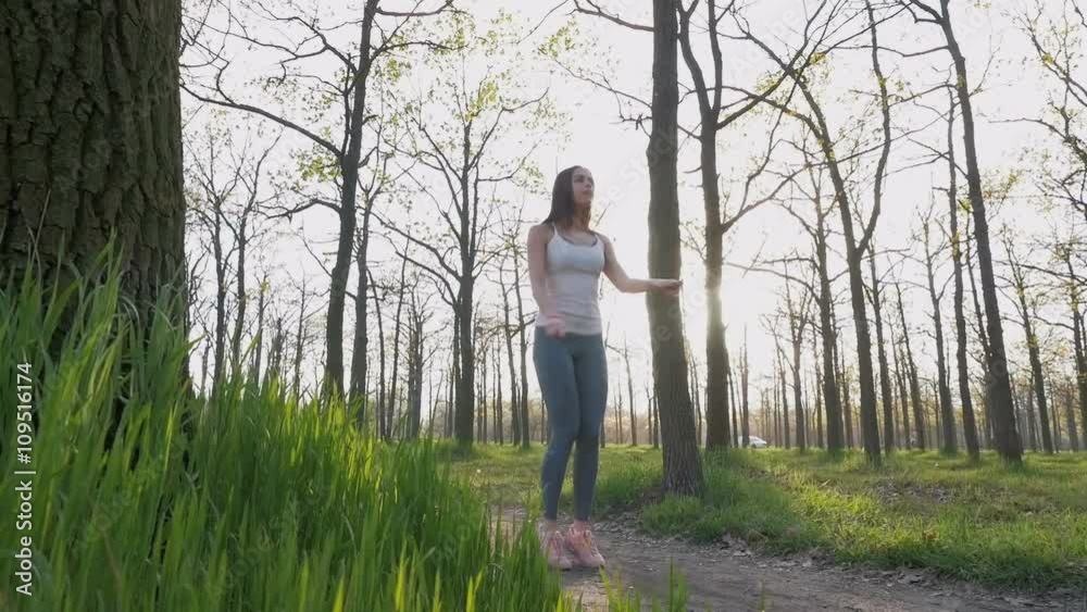 Young beautiful woman jumping rope in park at sunset, slow motion Young beautiful woman jumping rope in park at sunset, slow motion