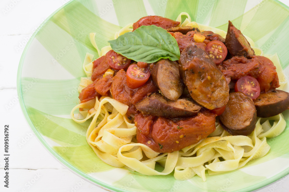 Chorizo sausage and tomato pasta meal with basil in plate isolat Chorizo sausage and tomato pasta meal with basil in plate isolat